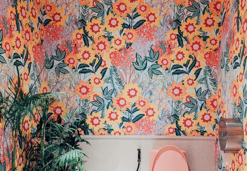 A bathroom with a toilet and a flowered wallpaper